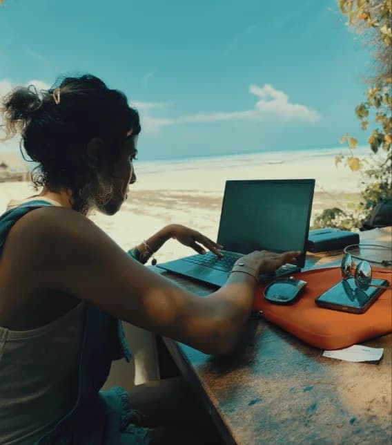 Hasna working on a laptop by the Zanzibar coast